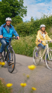 A person paddling a yellow kayak in the ocean near scenic coastal rock formations.