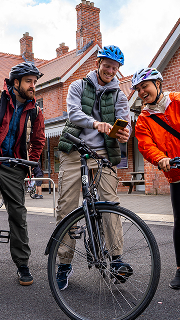 A group of people in wetsuits walking with blue surfboards toward the ocean for team building.